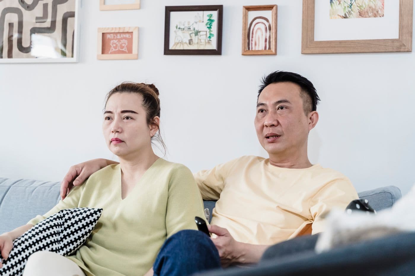 Pasangan duduk berdua di sofa ruang keluarga sambil menonton televisi bersama
